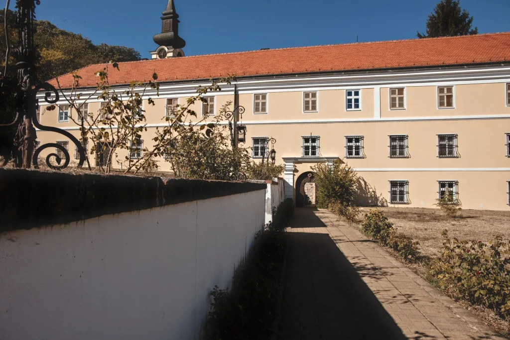 Popločana staza uz beli zid koja vodi do ulaza u konak manastira Novo Hopovo