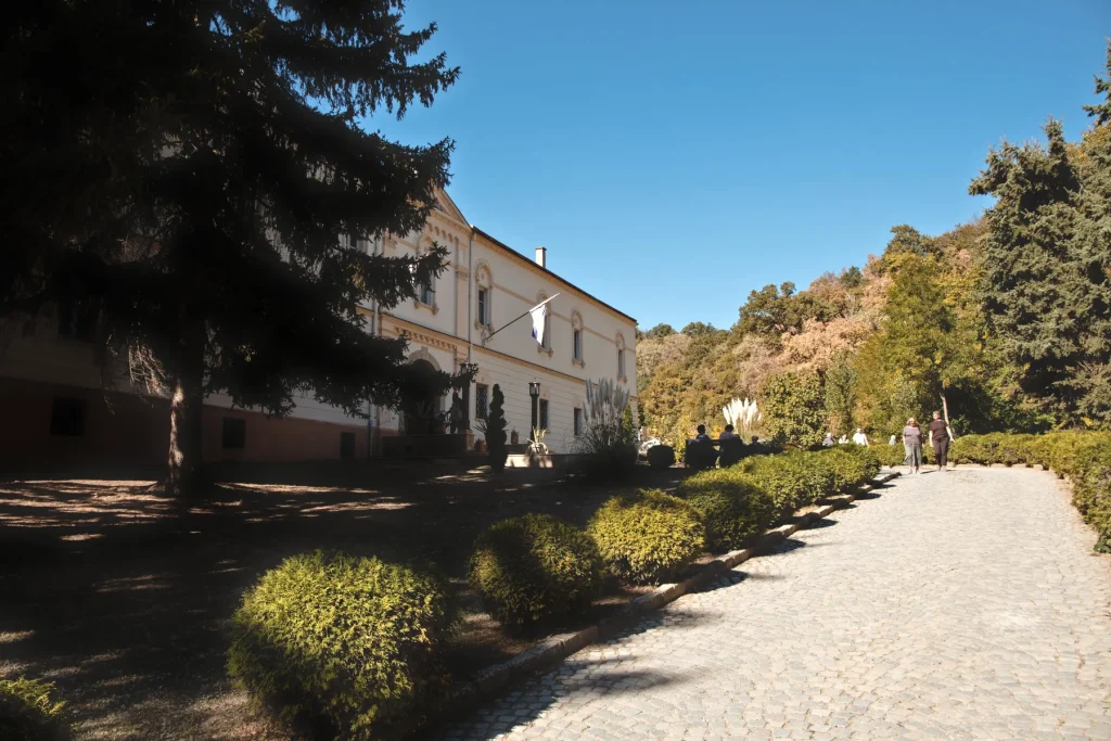 Popločana staza oivičena ukrasnim žbunjem, pored konaka manastira Grgeteg